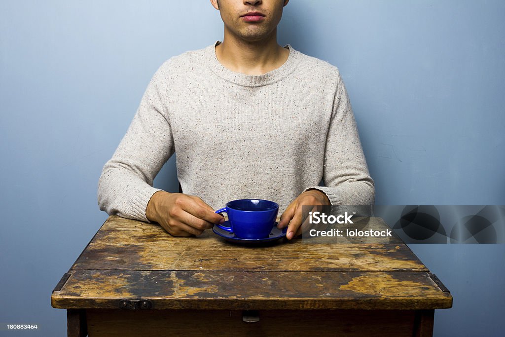 Hombre joven en mesa de madera beber de cup - Foto de stock de Adulto libre de derechos