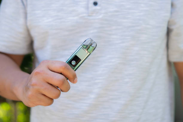 istock Disposable electronic cigarette in a man's hand on a nature background. 1808838766