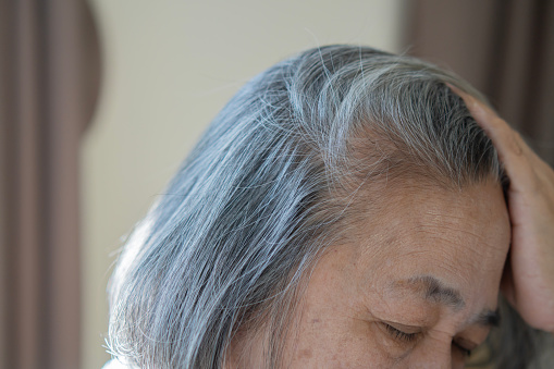 Closeup sad asian young beautiful woman and gray hair with worried stressed face expression looking down. White hair concept.