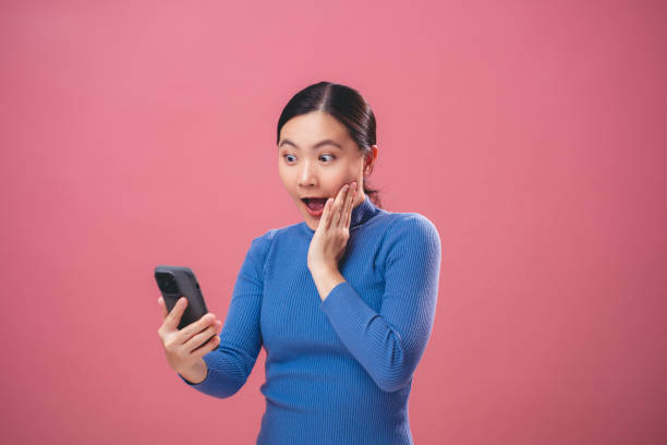 istock Asian woman happy excited using smartphone, isolated over pink background. 1808876363