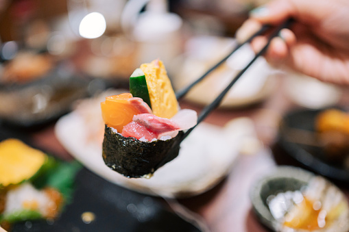 Set of rainbow uramaki sushi rolls with tuna, salmon and avocado, served in restaurant on bamboo mat