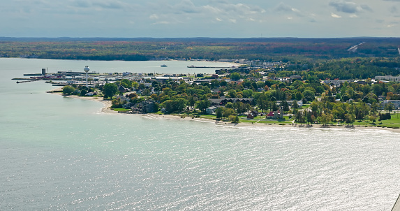 Aerial still image of Mackinaw City under a cloudy sky, with the lake up front.