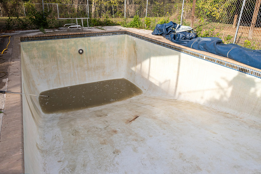 Green and dirty in ground pool during the cleaning process