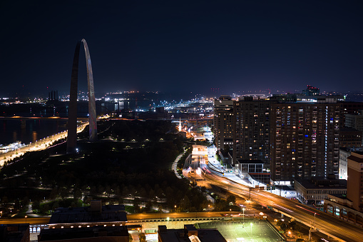Aerial still image of The Gateway Arch behind Eads Bridge and Martin Luther King Bridge, taken by a drone on a hazy night in St. Louis, Missouri.