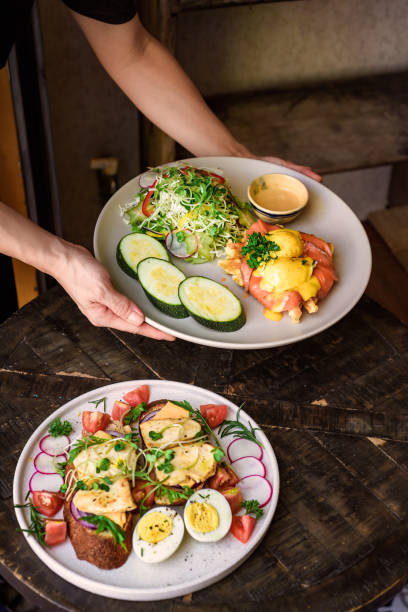 istock waitress holding a plate with eggs bennedict waffles with smoked salmon and serving on a table with chicken toasts in restaurant 1808902120