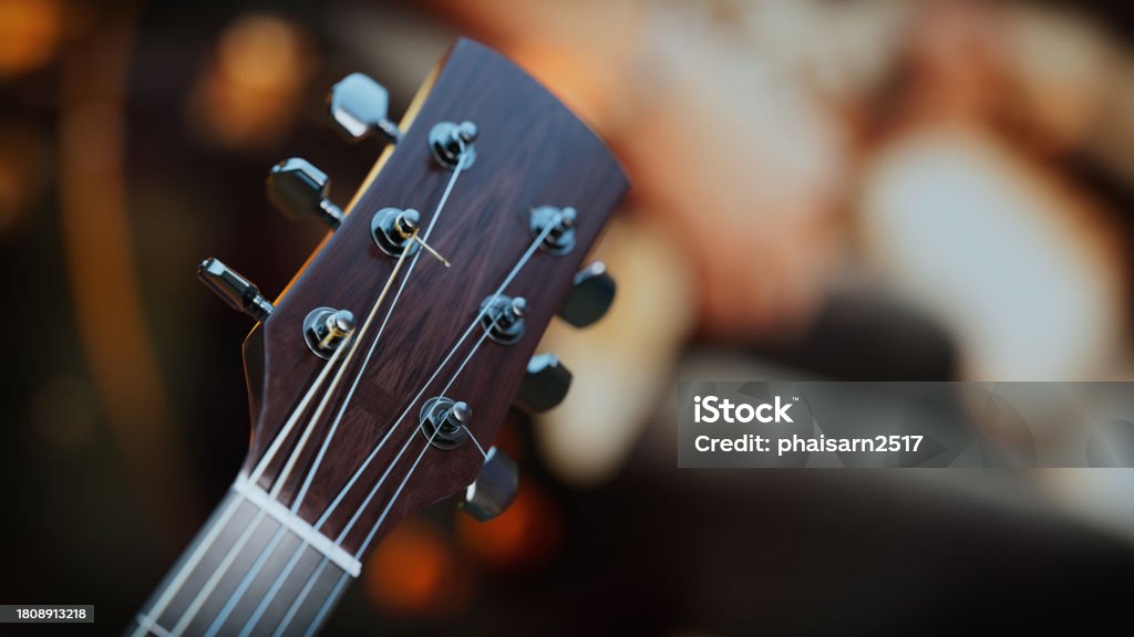 Close-up of an acoustic guitar . Close-up of an acoustic guitar head The guitar head is wood with silver accents. Behind him was a hand playing an electric guitar. Acoustic Music Stock Photo