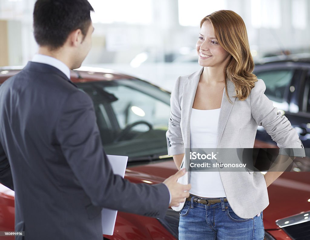 Car buyer Successful young lady discussing her potential purchase with a car dealer Adult Stock Photo