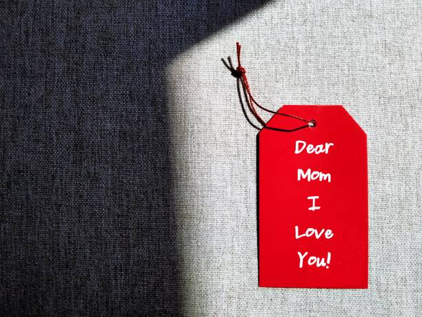 istock Red gift tag on copy space gray background with handwritten text DEAR MOM I LOVE YOU, concept of Happy Mother's Day card, honoring mother or to thank for all she's done and wish mom happiness 1808974096