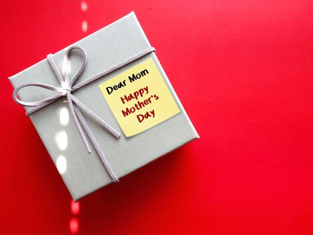 Gift box on red copy space baclground with handwritten text DEAR MOM, HAPPY MOTHER'S DAY, concept of express gratitude, honour mother unconditional love and make mom feel special