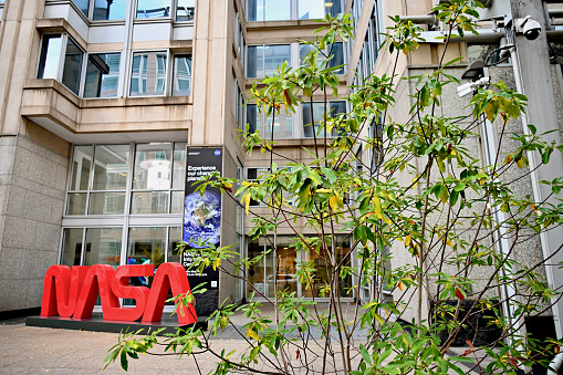 Washington, D.C., USA - November 20, 2023: A large, bright red “NASA” logo in front of the Mary W. Jackson NASA Headquarters building stands out on an overcast day in the Nation’s capital.
