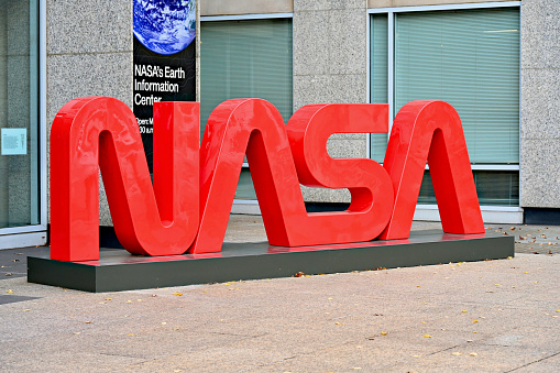 Washington, D.C., USA - November 20, 2023: A large, bright red “NASA” logo in front of the Mary W. Jackson NASA Headquarters building stands out on an overcast day in the Nation’s capital.