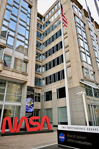 Washington, D.C., USA - November 20, 2023: A large, bright red “NASA” logo in front of the Mary W. Jackson NASA Headquarters building stands out on an overcast day in the Nation’s capital.