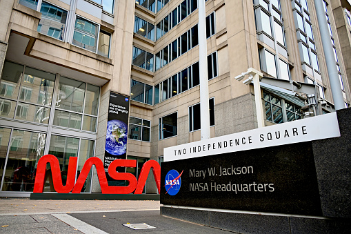 Washington, D.C., USA - November 20, 2023: A large, bright red “NASA” logo in front of the Mary W. Jackson NASA Headquarters building stands out on an overcast day in the Nation’s capital.