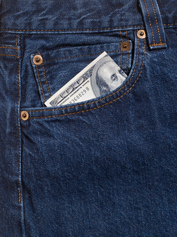 Close-up jeans detail photo in studio. There is 100 US dollars in your jeans pocket. No people.