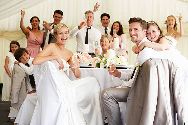 Bride And Groom Celebrating With Guests At Reception Bride And Groom Celebrating With Guests At Reception Smiling To Camera wedding reception photos stock pictures, royalty-free photos & images