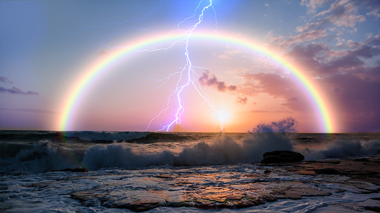 Rainbow over the stormy sea after rain with lightning, power sea wave in the foreground