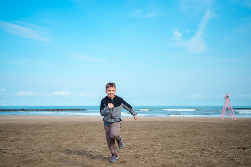 Little boy running at the beach next to sea