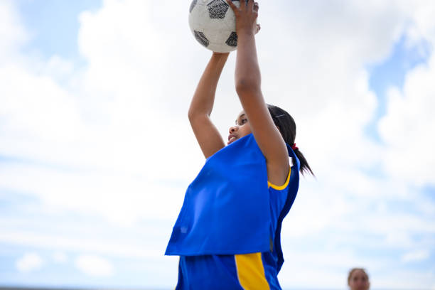 istock Low angle view girl catches ball playing netball at school 1809083007