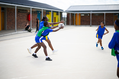Girls practicing netball in a school yard in a rural multiracial community