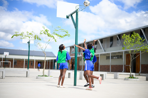 Girls practicing netball in a school yard in a rural multiracial community