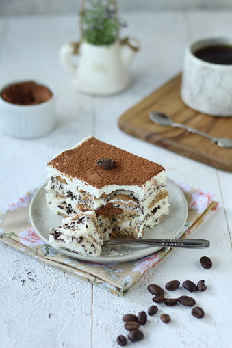 Close up on a portion of gourmet tiramisu Italian dessert topped with a coffee bean served on a plate at table in a side view