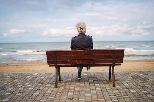 Woman looking at the view next to sea on a bench.