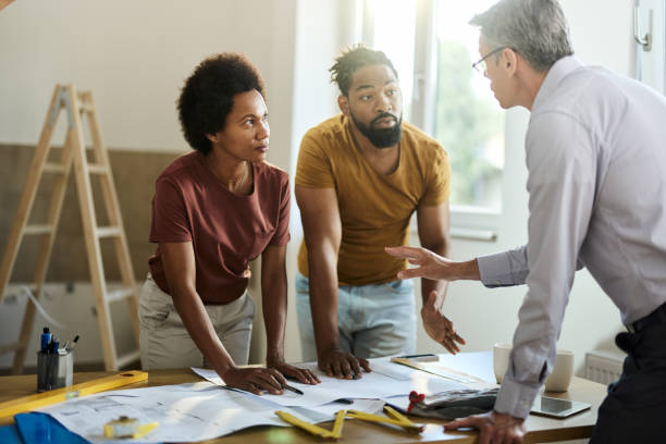 istock Black couple talking to architect while analyzing housing plan in the apartment. 1809094648