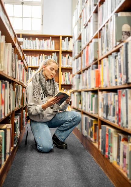 istock Young woman looking for a book in college library 1809110980