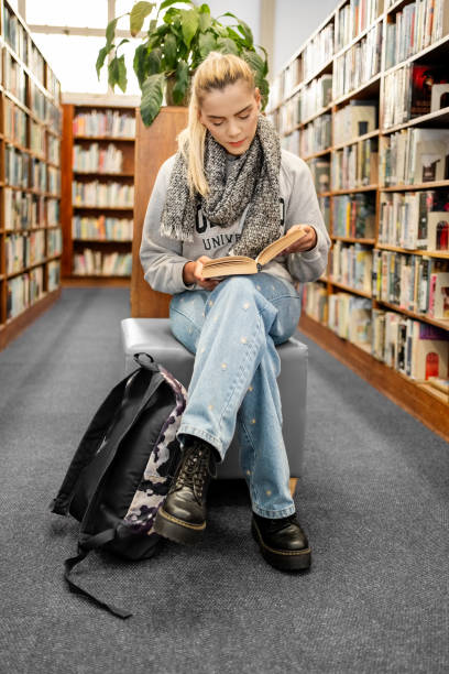 istock Young female student sitting in library and reading a book 1809114666