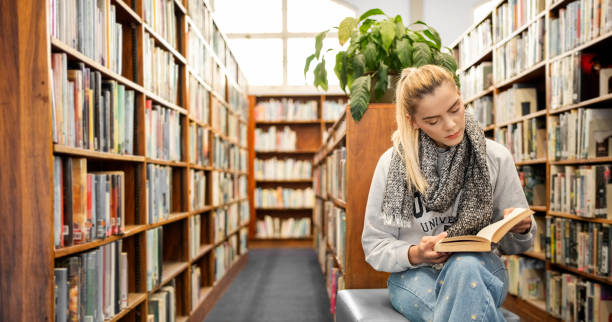 istock Female college student reading book in library 1809115195
