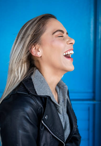 istock Cheerful young woman smiling against blue wall 1809121556