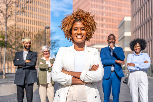 Frontal photo of a smiling african businesswoman standing next to colleagues