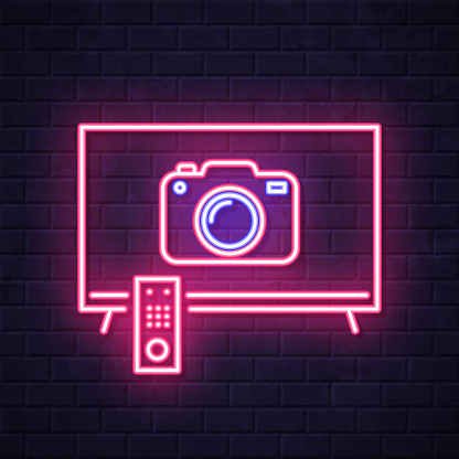 istock TV with camera. Glowing neon icon on brick wall background 1809125700