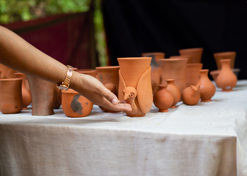 A human hand touching handmade pottery items in a roadside shop