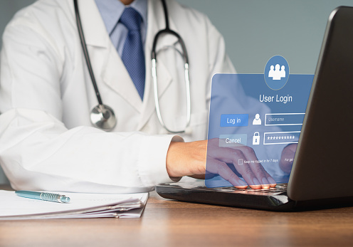 A doctor in a white coat logs into the system using a laptop. A page for the login interface. Concept of cyber security and personal data protection.