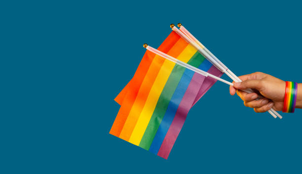 istock Rainbow flags showing in hand against a blue background 1809149154