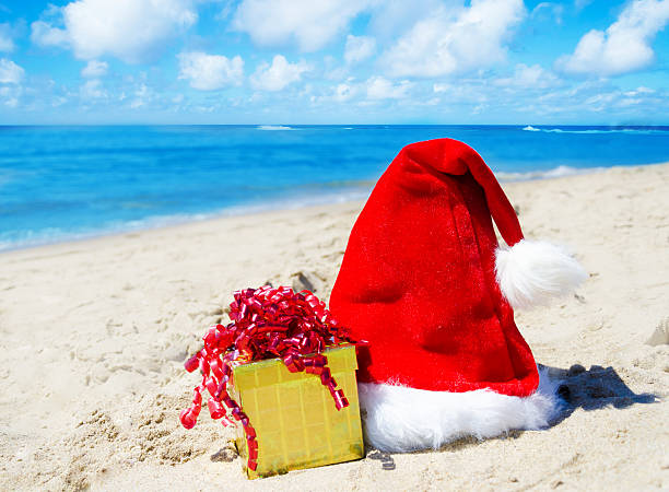 istock Christmas hat with gift box on the beach 180915867
