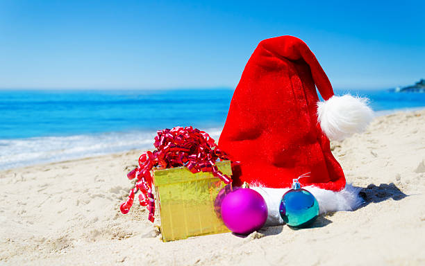 istock Christmas hat with gift box and balls on the beach 180915872