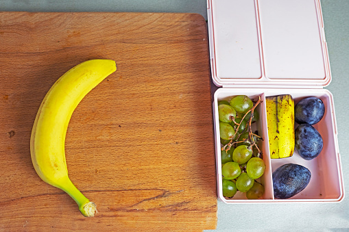 banana and a row of small containers with a snack. Back to school. flatlay