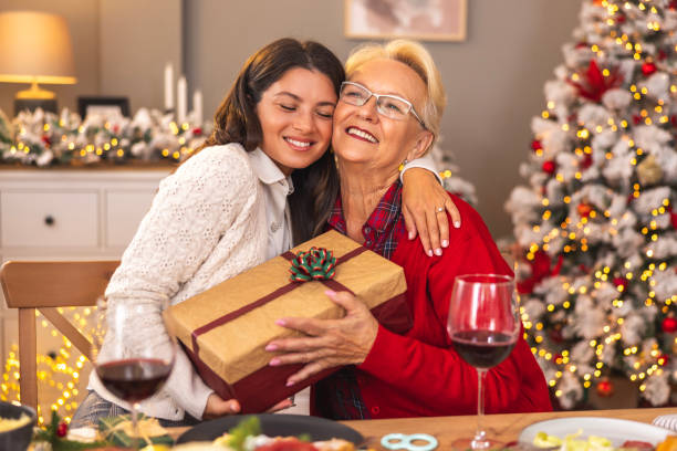 istock Mother and daughter exchanging presents while having Christmas dinner at home 1809197820