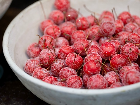 A bowl of frozen cherries covered in a layer of frost