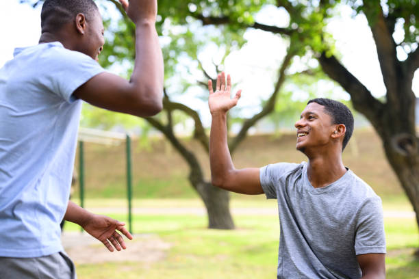 istock Friends high-five greeting in the park 1809239797