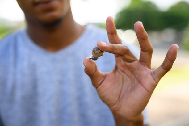 istock Close up man holding small hearing aid between fingers 1809241404