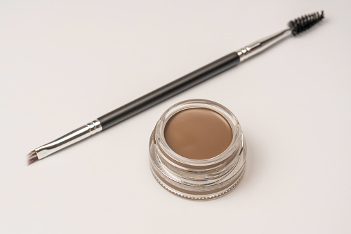 A brow pomade in blonde shade with brush isolated on a white background. Make up.