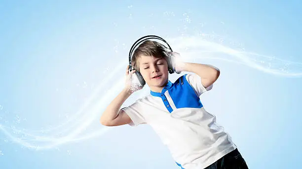 Little cute boy in headphones with eyes closed enjoying music
