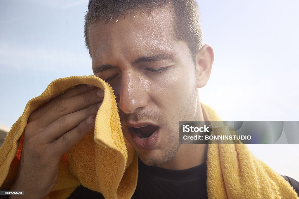 Young man wiping the sweat from his face with a towel sport man resting after a hard workout Sweat Stock Photo