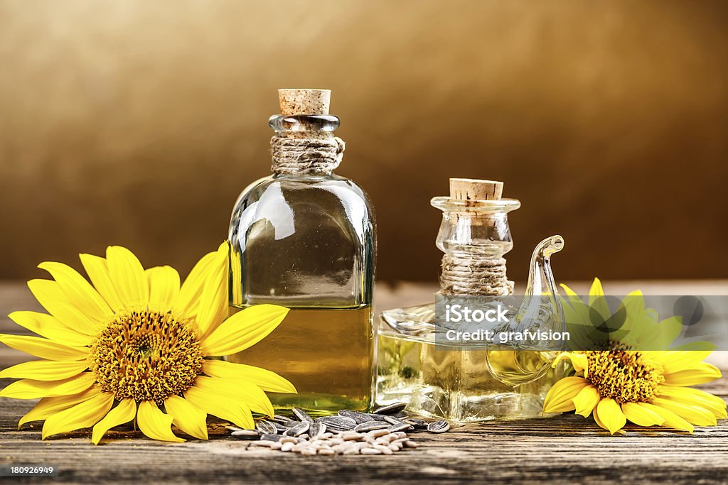 Two oil bottle Two oil bottle with sunflower on brown background Bottle Stock Photo