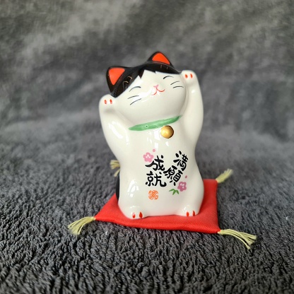 The maneki-neko (招き猫, lit. 'beckoning cat') is a common Japanese figurine which is often believed to bring good luck to the owner. In modern times, they are usually made of ceramic or plastic.