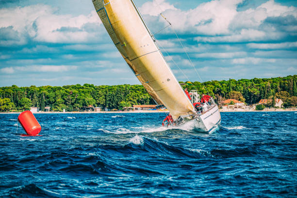 Sailing crew on sailboat turning on buoy on regatta. Models and event regatta property released.