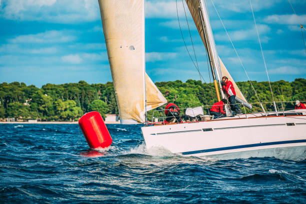 Sailing crew on sailboat turning on buoy on regatta. Models and event regatta property released.